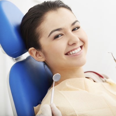 Young girl sitting in a blue dental chair and smiling