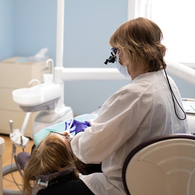 A dental hygienist performing a dental hygiene oral exam on a female patient